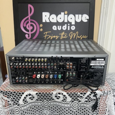 Rear panel of the Harman Kardon AVR 340 showing rows of RCA audio jacks, component video inputs, colour-coded speaker terminals and two AC outlets