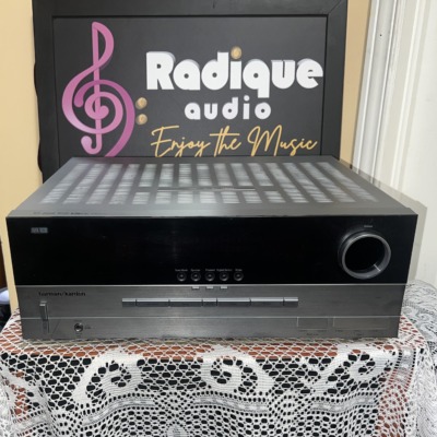 Harman Kardon AVR 340 AV receiver with a silver cabinet and gloss black front panel, large volume knob at the right and a row of buttons along the bottom