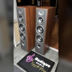Angled view of the JBL Northridge E80 towers, grilles off, showing the cherry side panels and grey front baffles