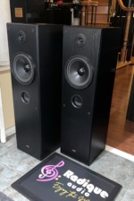 JVC SP-5500 towers at an angle with grilles off, showing the black woodgrain side panels, woofers and bass ports