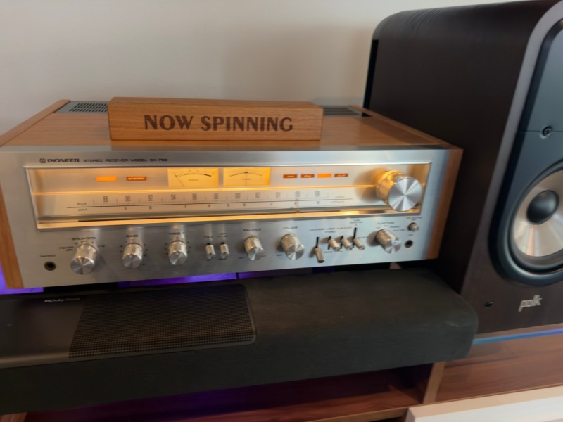 Kevin T.’s Pioneer SX-750 receiver in its Radique cherry cabinet, with a Now Spinning sign on top and a Polk speaker beside it