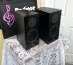 Linn Katan bookshelf speakers in black ash seen at an angle, a staggered pair showing the cabinet sides, tweeters and mid/bass drivers