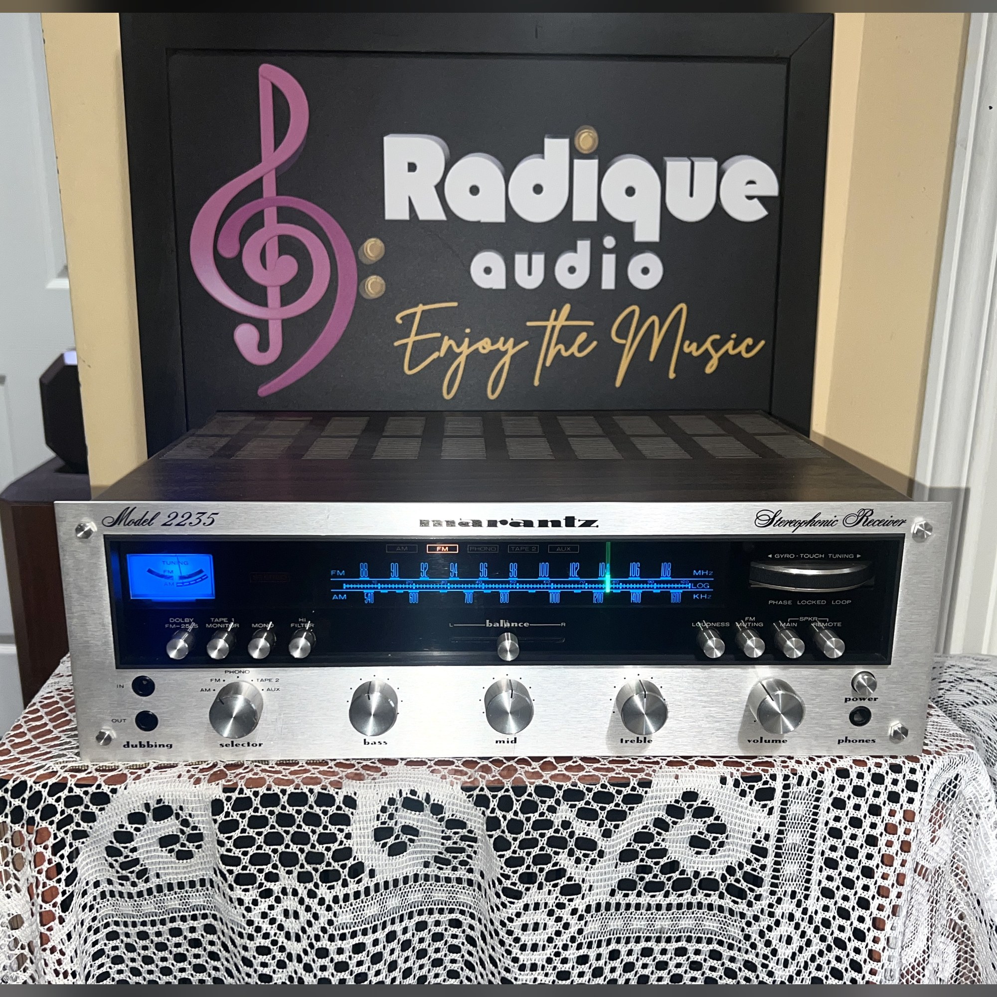 Marantz-2235-Stereo-Receiver-Front-Thumb Marantz 2235 stereo receiver, silver faceplate with blue-lit tuning dial and tuning meter, a row of toggle switches and rotary tone and volume knobs
