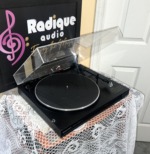 Marantz TT151 turntable from the side with the dust cover raised, black mat on the platter and the tonearm and headshell at right