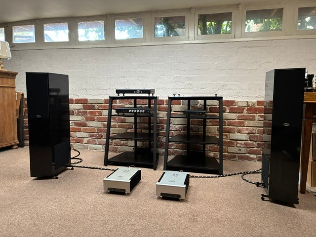 Marcello R.’s listening room in Atwater, California: NHT 2.5i towers either side of two black equipment racks, with a pair of silver mono amplifiers on the floor