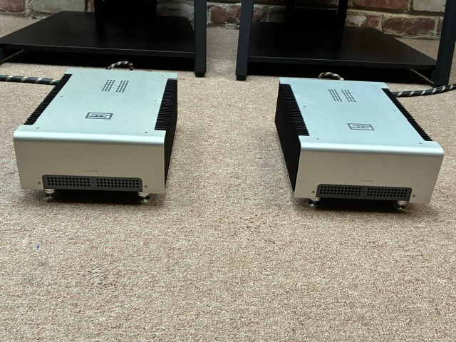 Marcello R.’s pair of silver mono power amplifiers on the carpet in front of his equipment racks