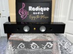 Monitor Audio Radius 250HD centre speaker lying horizontal, straight-on view of two silver woofers either side of a gold tweeter