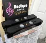 Two Monitor Audio Radius 250HD speakers stacked horizontally at an angle, grilles removed to show the silver cones and gold tweeters