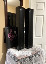 Pair of Monitor Audio Radius 250HD speakers standing upright with grilles on, tall slim gloss black cabinets side by side