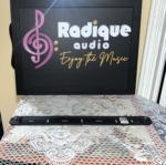 One Monitor Audio Radius 250HD wall bracket laid flat, a slim black metal rail with slots for the wall screws and a stand-off at each end