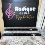 Two Monitor Audio Radius 250HD wall brackets side by side, slim black metal rails with slots for the wall screws and a stand-off at each end