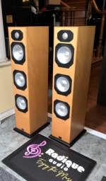 Pair of Monitor Audio Silver S8 towers at an angle, light wood-veneer cabinets on black plinths with silver drivers