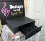NAD 513 CD player at an angle with its drawer open, showing the three-disc carousel tray inside the grey case