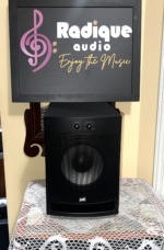 PSB Alpha SubZero i subwoofer with its perforated metal grille fitted, PSB logo at the base and volume and crossover dials above