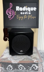 PSB SubSeries HD10 powered subwoofer front view, compact satin black cabinet with a black mesh grille over the front driver