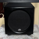 PSB SubSeries HD10 powered subwoofer front view, compact satin black cabinet with a black mesh grille over the front driver