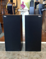 Paisley Reference Two speaker pair with black cloth grilles fitted, a small Paisley badge in the top corner of each grille