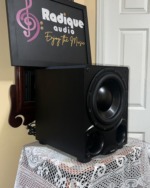 Paradigm DSP-3100 v.2 subwoofer at an angle with grille off, showing the black cabinet side and front-firing woofer