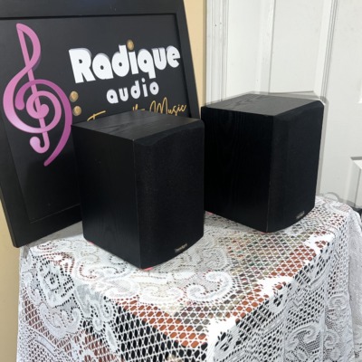 Paradigm Micro v.3 speaker pair at an angle, black ash vinyl cabinets with grilles on and the badge at the lower corner