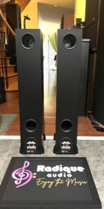 Rear of the Paradigm Monitor 7 v.6 pair showing the upper and lower bass ports and the binding-post terminal cups with model labels