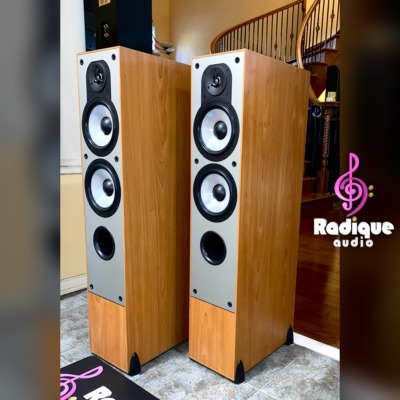 Paradigm Monitor 7 v2 towers at an angle with grilles on, slim light cherry cabinets and black cloth fronts