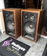 Angled view of the Pioneer CS-77 pair with grilles off, showing the walnut side panels and black driver baffles