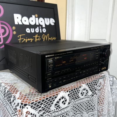 Pioneer VSX-9900S receiver from the left at an angle, black case with vented top, lit display and large volume knob on the right
