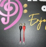 Pair of Radique Audio small spade adapters, red and black, clear-topped banana sockets above small spade forks