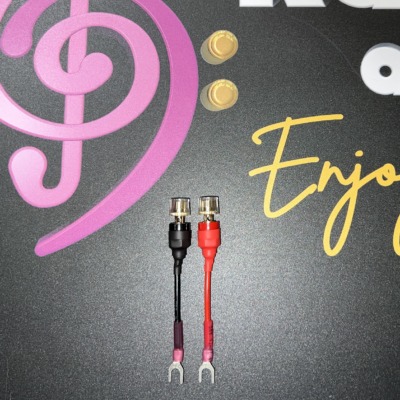 Pair of Radique Audio small spade adapters, red and black, clear-topped banana sockets above small spade forks