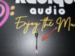 Radique Audio small spade adapters laid apart, the black one upright and the red one angled across the card