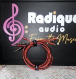 Pair of red and black Radique House CCA speaker cables, 10 ft, coiled upright with pin connectors and small spades