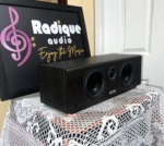Tannoy Mercury FC Custom center speaker at an angle, grille off, showing the dark woodgrain side panel and three front drivers