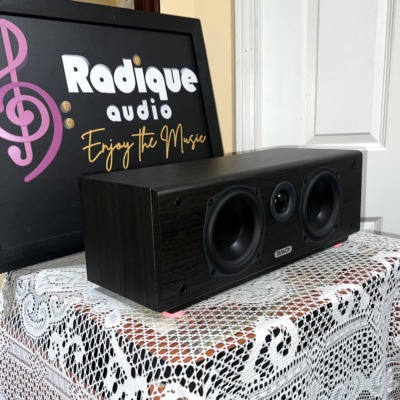 Tannoy Mercury FC Custom center speaker at an angle, grille off, showing the dark woodgrain side panel and three front drivers