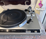Close-up of the Technics SL-220 tonearm carrying an ivory Piezo cartridge on a black universal headshell, beside the strobe ring