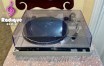 Technics SL-220 belt-drive turntable from the front with its clear dust cover closed, silver plinth and Technics control strip