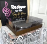 Yamaha YP-211 turntable from a front angle, clear dust cover closed over the silver platter on a wood-grain plinth