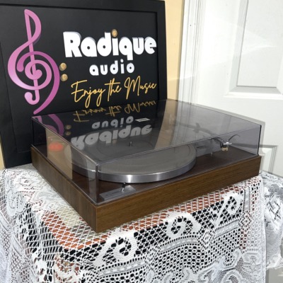 Yamaha YP-211 turntable from a front angle, clear dust cover closed over the silver platter on a wood-grain plinth