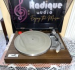 Yamaha YP-211 turntable from above with the lid raised, ribbed silver platter, tonearm on its rest and a red knob at the rear left